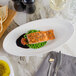 A slanted white porcelain bowl with a piece of food in it.