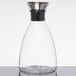 A clear glass decanter with a stainless steel lid.