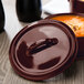 A brown Bon Chef porcelain oval cocotte lid with a handle.