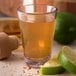 A Carlisle dessert shot glass filled with brown liquid and limes.