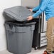 A man opening a Rubbermaid BRUTE 40 gallon trash can in a school kitchen.