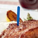 A piece of steak with a blue plastic steak marker in it.