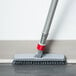 A Unger SmartColor Swivel Corner Brush with a white handle on the floor.