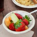 A Solo Symphony heavy weight paper bowl filled with fruit on a table.