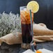 A glass of iced tea with a lemon slice and a Walco stainless steel iced tea spoon.