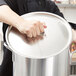 A person holding a Vollrath aluminum pot cover over a silver pot.