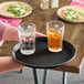 A hand holding a Cambro non-skid serving tray with a glass of ice tea and two glasses of liquid.
