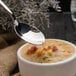 A Walco stainless steel bouillon spoon over a bowl of soup.