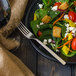 A plate of salad with a Walco stainless steel salad fork next to it.
