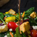 A Walco stainless steel salad fork in a salad with spinach, tomatoes, and feta.