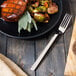 A plate of food with a Walco European table fork on a table.