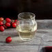 A Chef & Sommelier Macaron rocks glass filled with red wine on a wood table.