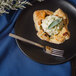 A Walco stainless steel dinner fork on a plate with a pastry.