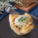 A Walco stainless steel dinner fork picking up a pastry with cream and herbs.