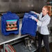 A woman in a white coat and gloves holding a blue container with food in it.