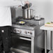 A person cooking food on a Cooking Performance Group 36" step-up gas range.