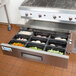 A stainless steel drawer with food inside it over a container of food.