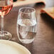 A Chef & Sommelier highball glass of water next to a plate of wine.