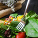 A Walco stainless steel salad fork in a bowl of salad.