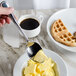 A person using a Walco Pacific Rim tablespoon to put butter on a waffle.