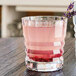 A Chef & Sommelier Cristal d'Arques Architecte rocks glass with pink liquid and a lavender flower.