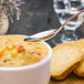 A Walco stainless steel bouillon spoon in a bowl of soup.