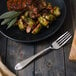 A plate of food next to a Walco Art Deco stainless steel dinner fork.