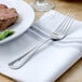 A Walco Pacific Rim stainless steel dinner fork on a plate of food.