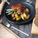 A Walco Erik stainless steel dinner fork next to a plate of food with brussels sprouts.