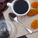 A cup of coffee with a Walco Luxor stainless steel demitasse spoon on a saucer.