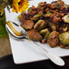 A Walco stainless steel serving spoon on a plate of food.