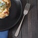 A plate with food on it next to a Walco Star stainless steel dinner fork.