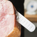 A Mercer Culinary Praxis® slicer knife cutting a piece of meat.