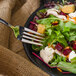 A Walco Art Deco stainless steel salad fork on a plate of salad with beets, carrots, and cauliflower.