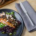 A plate of food with a Walco Pacific Rim stainless steel dinner knife on a napkin.