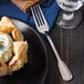 A Walco Luxor stainless steel dinner fork on a blue napkin