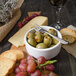 A bowl of green olives with a Walco stainless steel cocktail fork.