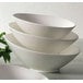 A stack of CAC bone white porcelain salad bowls.