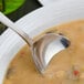 A Walco Pacific Rim stainless steel bouillon spoon in a bowl of soup.