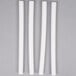Four white plastic Wilton cake dowel rods.