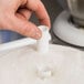A hand using a Wilton plastic cake dowel rod to support a cake.