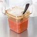 A person in gloves holding a Carlisle High Heat plastic container of food.