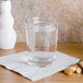 A Libbey side water glass of water on a table with nuts.