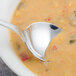 A Walco stainless steel bouillon spoon in a bowl of soup.