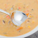 A Walco stainless steel bouillon spoon in a bowl of soup.