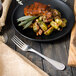 A Walco stainless steel European table fork next to a plate of food on a table.