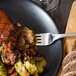 A plate of food with a Walco stainless steel European table fork on a table in a farm-to-table restaurant.