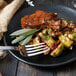 A plate of food with a Walco Bosa Nova table fork next to meat and brussels sprouts.