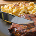 A Walco Saville dinner knife cutting macaroni and cheese on a plate.