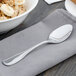 A Walco stainless steel teaspoon on a napkin next to a bowl of cereal.